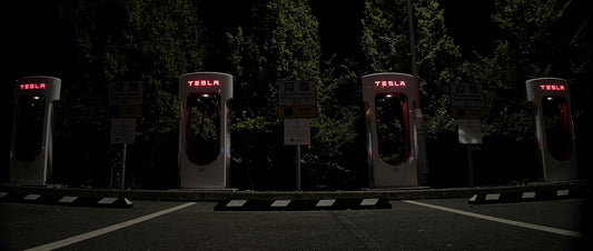 a row of gas pumps in a parking lot at night