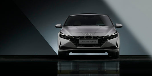 the front end of a silver car in a dark room