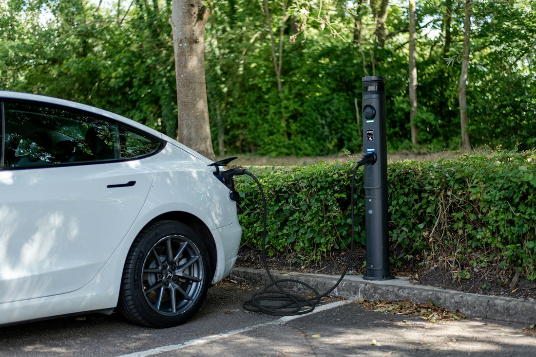 White electric car plugged in at a charging station.