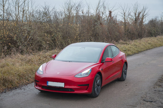 Red tesla car parked on a dirt road